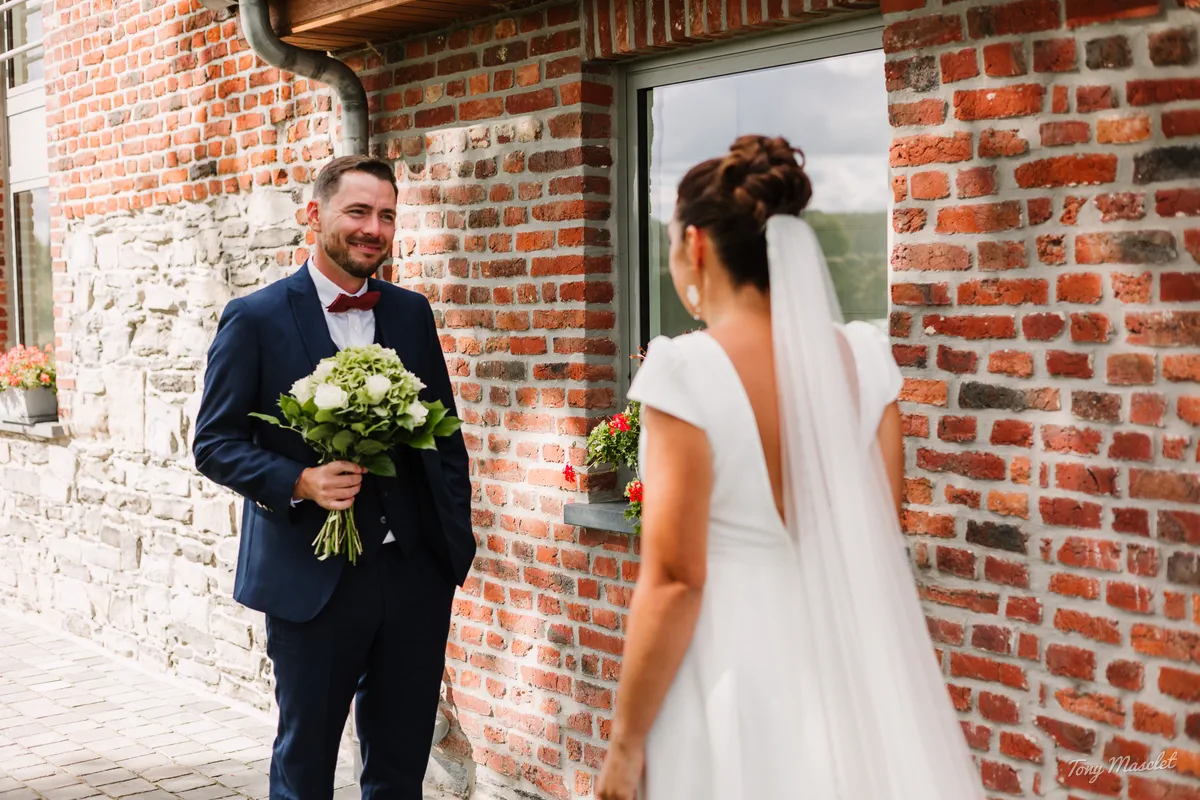 Mariage Clos de la Conciergerie Brunehaut – first look devant la façade en brique rouge, Aurélien découvre Aurélie
