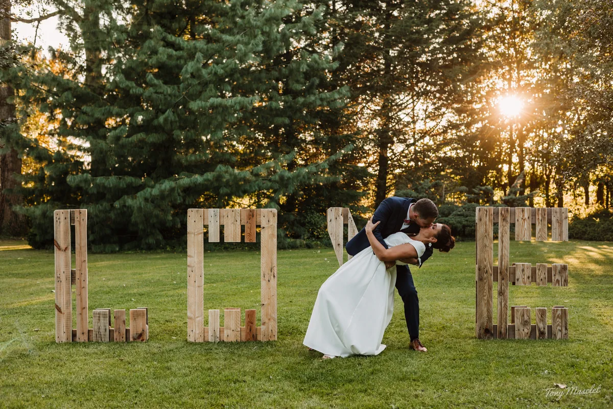 Photographe mariage Clos de la Conciergerie – baiser romantique devant les lettres LOVE au coucher du soleil