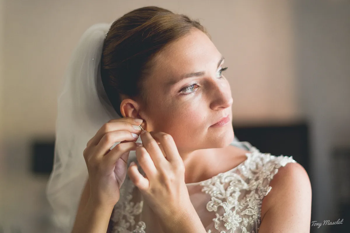 Photographe mariage Nieppe – portrait de la mariée mettant ses boucles d'oreilles en lumière naturelle