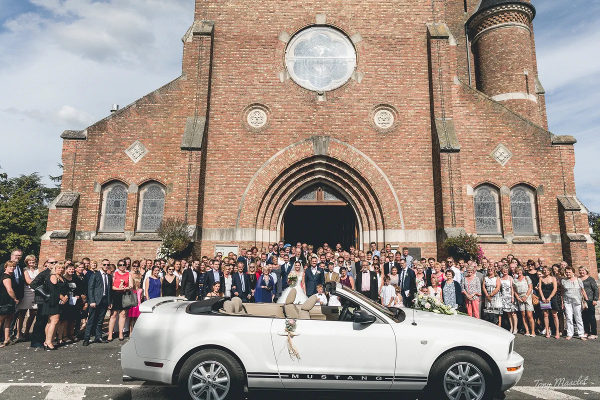 Photographe mariage Nieppe – photo de groupe devant l'église avec Mustang décapotable