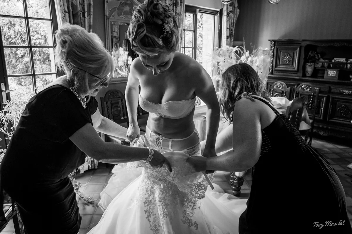 Photographe mariage Nieppe – habillage de la mariée, laçage du corset de la robe en dentelle