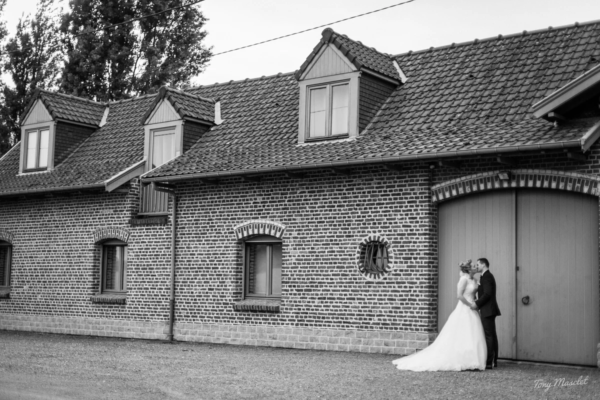 Photographe mariage Nieppe – baiser du couple devant la façade en briques du Clos du Bac