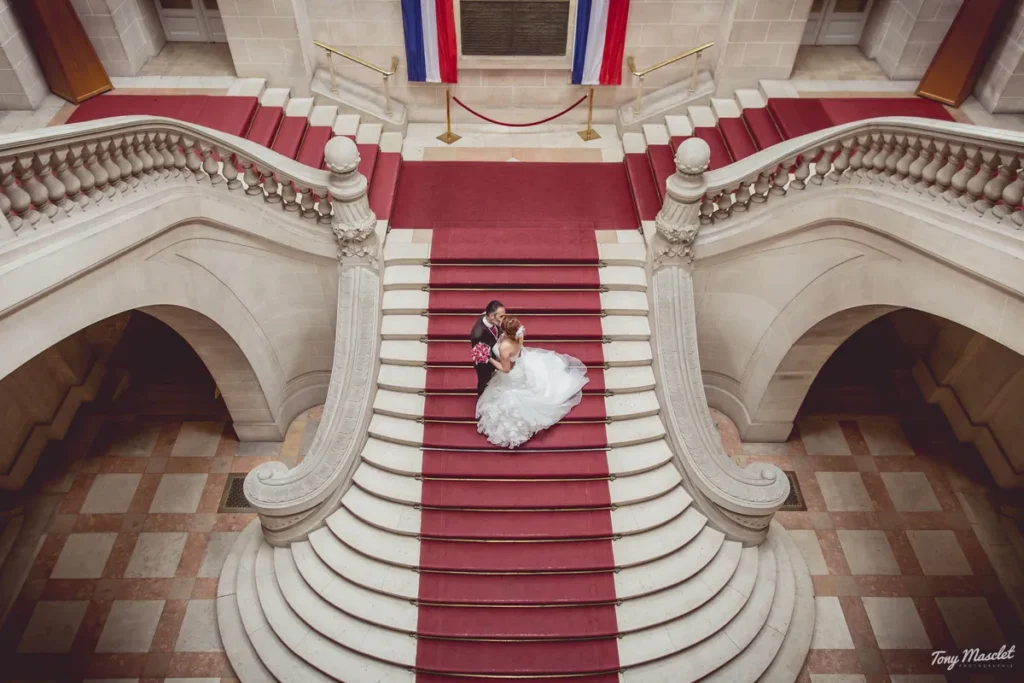 Mariés vus du balcon dans l'escalier de la mairie de Roubaix - Photographe mariage Tony Masclet