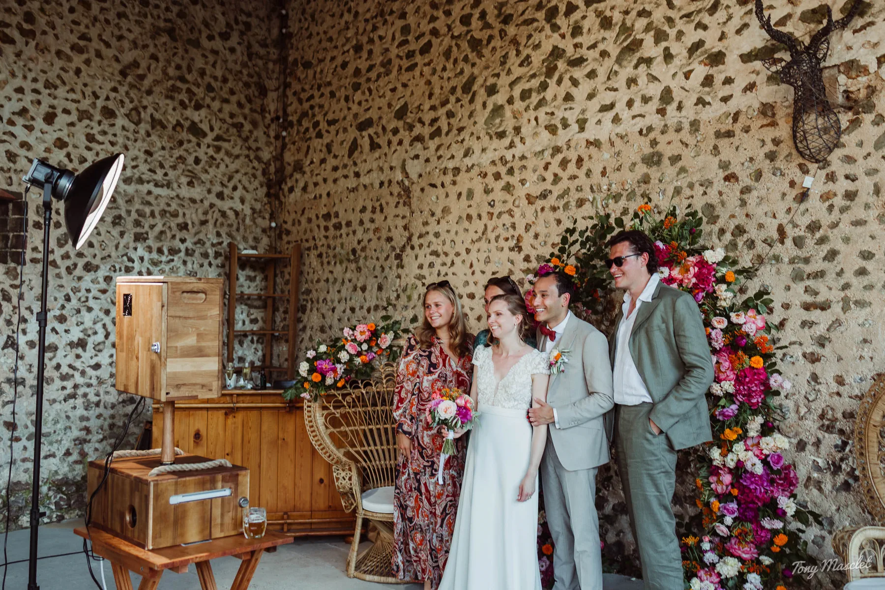 Photo de groupe naturelle devant le Photobooth artisanal en bois lors d'un mariage